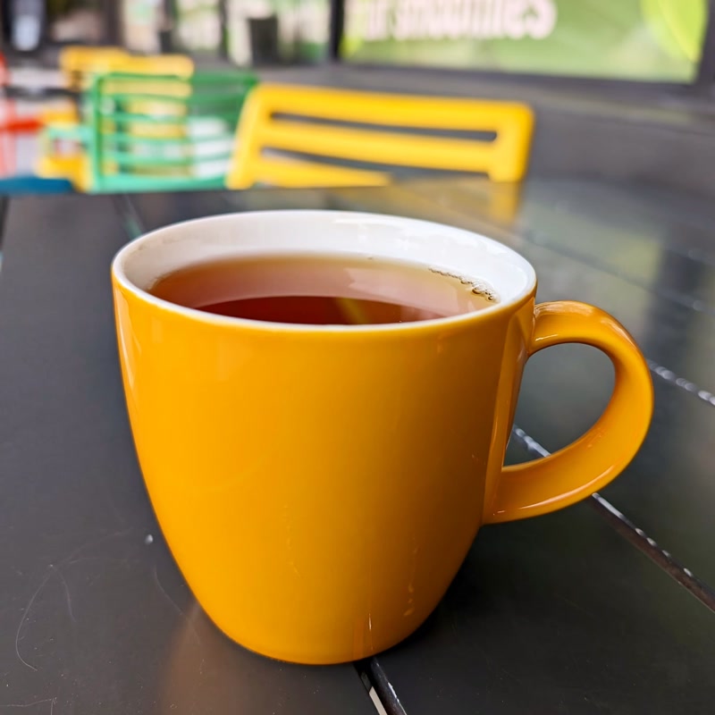 Hot loose leaf tea in a yellow mug on the colorful patio at specialTEA Lounge, Miami
